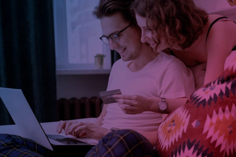 lächelnder Mann und Frau vor Laptop mit Kreditkarte