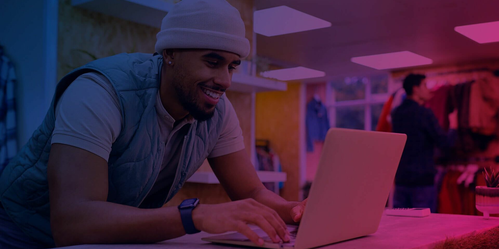 lächelnde Person mit Mütze vor Laptop